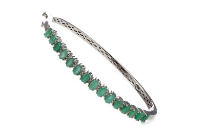 Lot 1307 - A WHITE TOPAZ AND EMERALD BANGLE